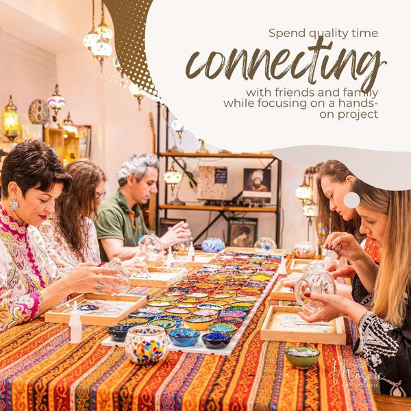 Group of people creating mosaic art with colorful tiles and glassware in a well-lit studio