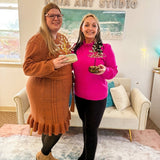 Two smiling participants holding their finished wire trees after the Wire Tree Art Workshop