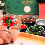 Hand holding glass candle holder decorated with red and green mosaic star in art studio DIY kit
