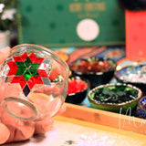 Hand holding glass candle holder decorated with red and green mosaic star in art studio DIY kit